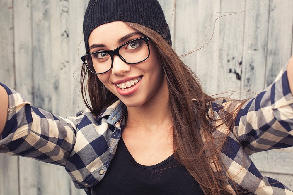 teen girl smiling with ceramic braces taking selfie