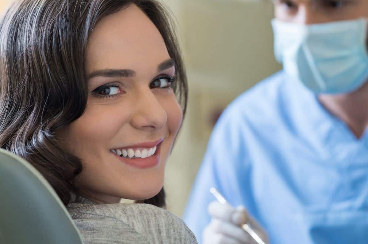 Woman in dentist chair smiling over her shoulder at the camera.